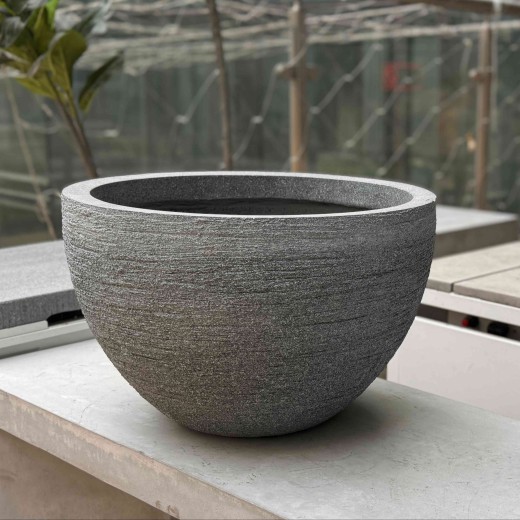 Large 36 inch cement pots for indoor plants on long concrete bench.